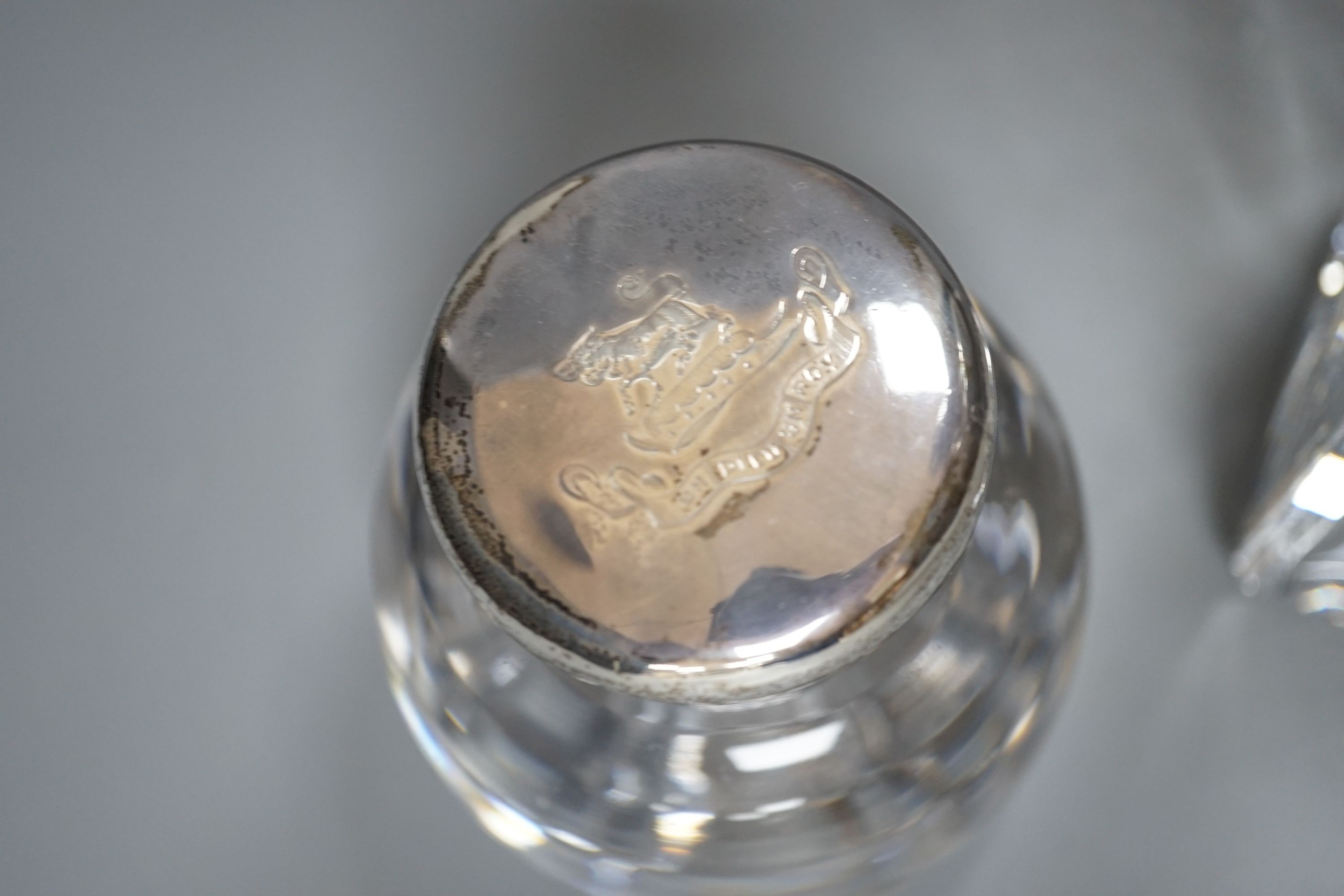 A Victorian circular heavy glass inkwell with hinged silver lid, engraved crest (London 1892) and a silver mounted decanter, 26.5cm